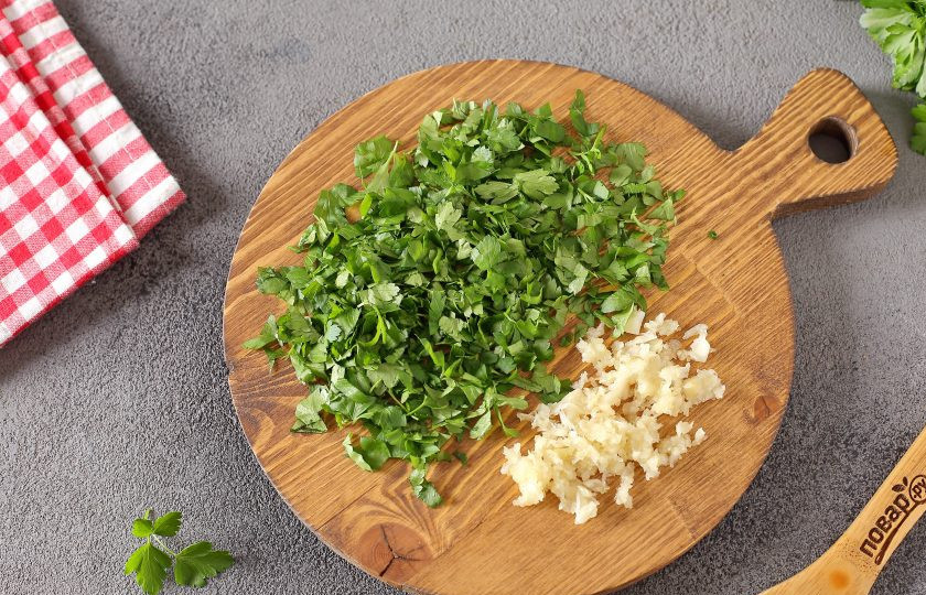 1. Этап. Салат из огурцов с чесноком на зиму: Зелень измельчите ножом, чеснок пропустите через пресс.