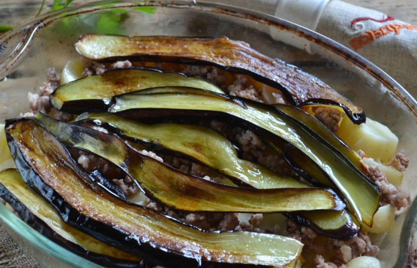 1. Этап. Мусака классический рецепт: 4. Баклажаны порежьте вдоль на тонкие пластины и обжарьте на сковороде в растительном масле. Разложите готовые баклажаны сверху на фарш, а масло, в котором они жарились, вылейте сверху.