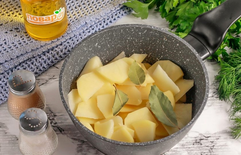 1. Этап. Картофельное пюре с йогуртом и базиликом: Клубни нарежьте ломтиками в казан или ковш с антипригарным дном. Добавьте туда же лавровые листья, соль и влейте горячую воду, чтобы она покрыла нарезку картофеля.