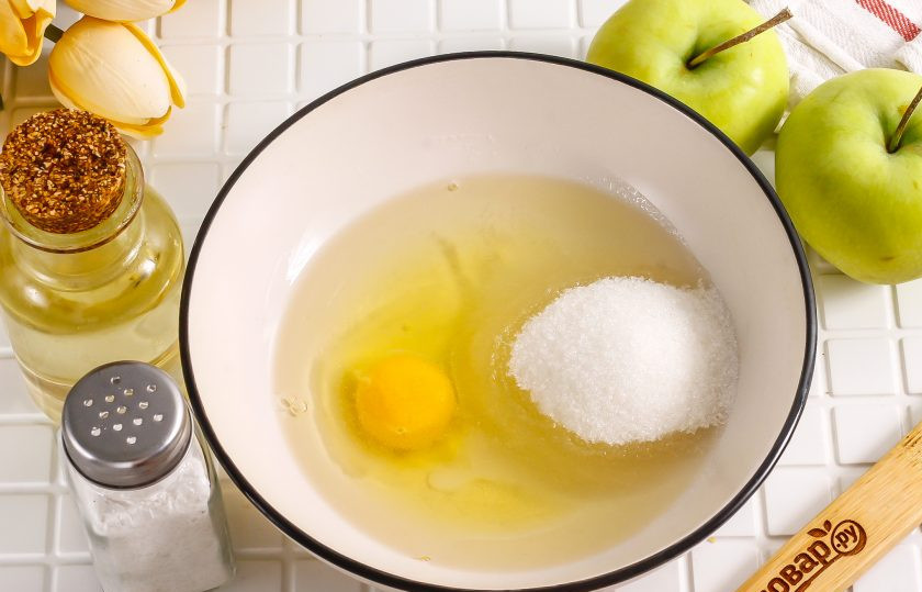 1. Этап. Песочный пирог с вареньем и яблоками: Влейте растительное масло без запаха в глубокую емкость, вбейте туда же куриное яйцо, всыпьте сахар и соль. Тщательно взбейте.