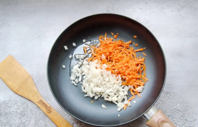 1. Этап. Гороховая каша по-английски: А пока горох варится, лук и морковь очистите, помойте. Лук мелко нарежьте, а морковь натрите на терке. Выложите в сковороду с подсолнечным маслом.