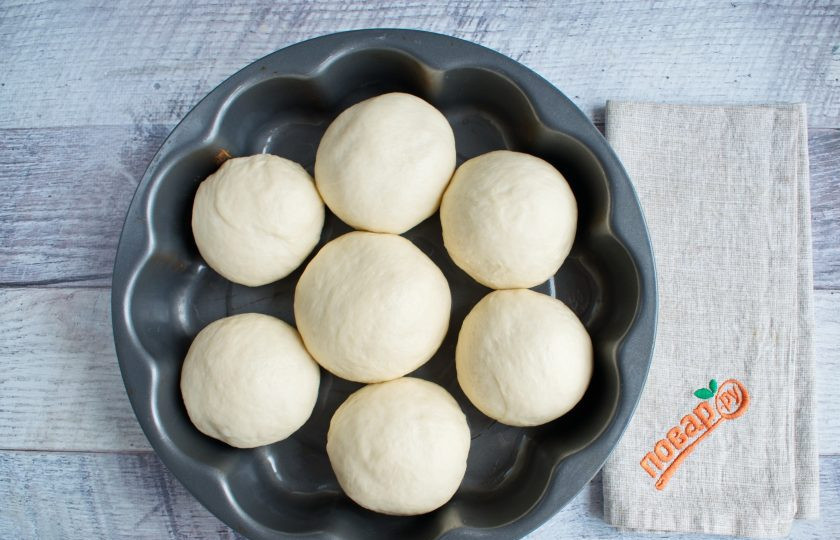 1. Этап. Булочка Ромашка: Разделите тесто на 7 равных частей. Каждую примните в круглую лепешку, соберите тесто в центр, переверните и округлите. Круглые заготовки положите в виде цветка в форму (23 см), смазанную маслом. Накройте пищевой пленкой, поставьте в теплое место для подхода на 40 минут.