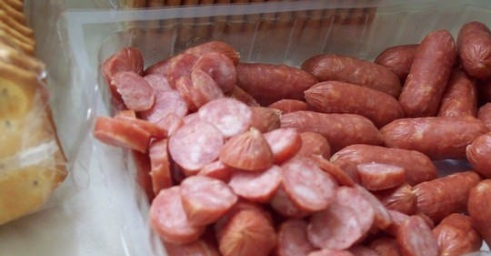 1. Этап. Закуска на крекерах с сыром и сосисками: Колбаску или сосиски нарежьте кружками. Помидоры помойте и нарежьте дольками.