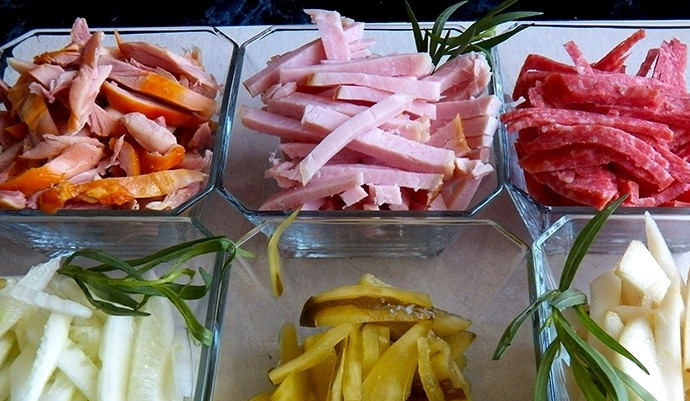 1. Этап. Салат Новогоднее настроение: Сервелат и карбонад также нарежьте соломкой. Вместо этих ингредиентов вы можете использовать и любимую колбаску или ветчину. Копченые куриные окорочка нарежьте, достав из них кости.