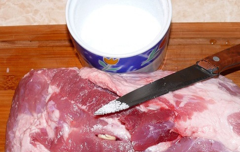 1. Этап. Свиная шея, запеченная в фольге: Нож опускаем в соль и делаем в мясе много надрезов, в которые вставляем чеснок.