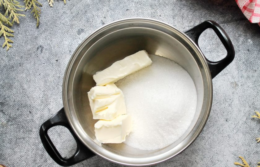 1. Этап. Трюфели из сухого молока: В кастрюлю с толстым дном налейте воду, всыпьте сахар и добавьте сливочное масло.