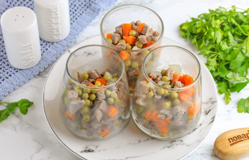 1. Этап. Заливное Провансаль из говядины: Перемешайте нарезки с зеленым горошком и выложите в стаканы или пиалы на 2/3 объема емкости.