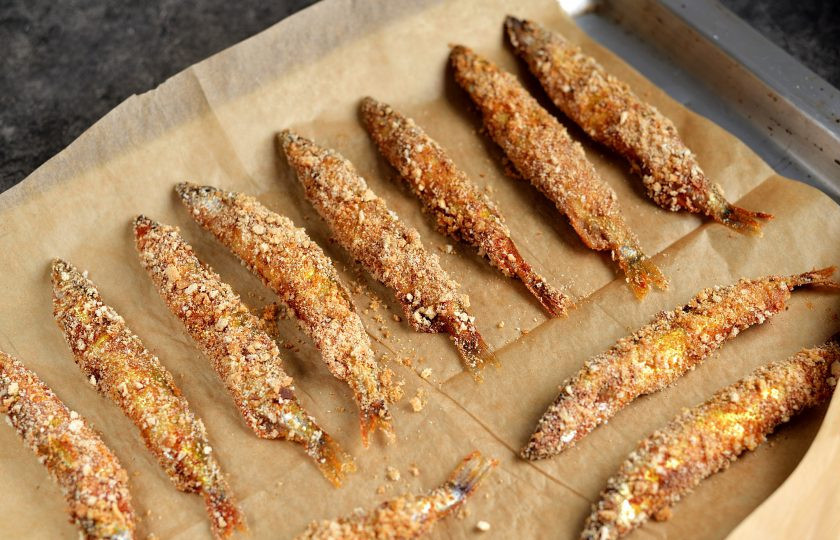 1. Этап. Мойва с корочкой в духовке: Выстелите противень пергаментом, выложите мойву на небольшом расстоянии друг от друга и отправьте в предварительно разогретую до 200 градусов духовку на 20-25 минут. Запекать рыбку следует в режиме верхнего и нижнего нагрева, противень установите посередине духовки.