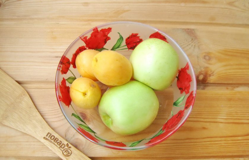 1. Этап. Компот из абрикосов и яблок на зиму: Тщательно вымойте фрукты. У яблок удалите плодоножку и сердцевину. Нарежьте дольками. Абрикосы разрежьте на половинки и удалите косточку.