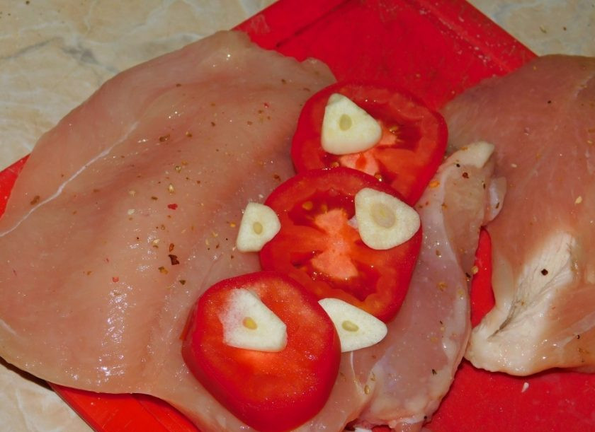 1. Этап. Запеченная куриная грудка с помидорами и чесноком: На одну половину грудок выложите помидоры и немного чеснока.