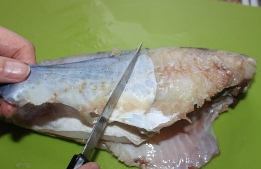 1. Этап. Жареная пикша: 1. Рыбку выкладываю на разделочную доску, отрезаю голову, хвост и плавники, очищаю от чешуи. Острым ножом делаю надрез возле головы и подцепляю кожу, снимаю ее по направлению к хвосту.