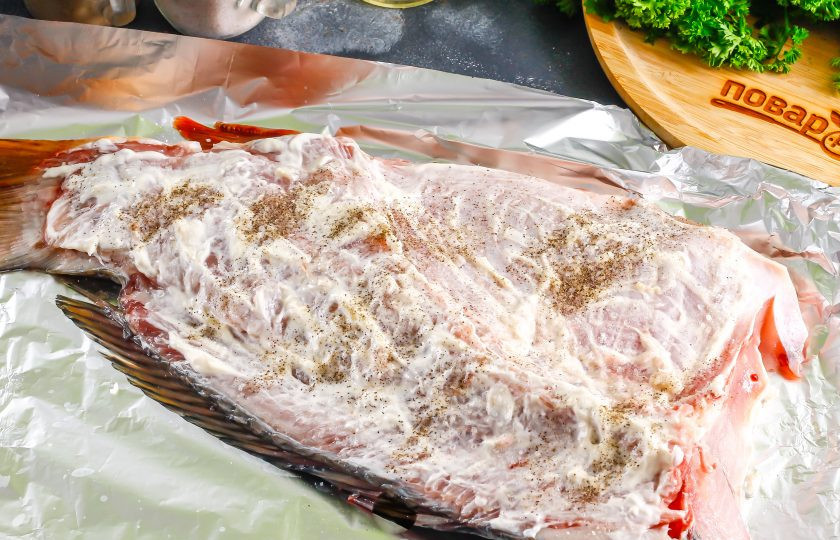 1. Этап. Сазан в духовке с лимоном: Выложите часть рыбы на фольгу или противень, смазав их растительным маслом. Помните, что кожура рыбы прилипнет к противню при запекании, поэтому лучше все же застелить его фольгой или пергаментной бумагой. Выдавите из лимона немного сока, смажьте поверхность тушки, посолите и поперчите, размажьте специи по рыбе. Выложите майонез любой жирности и обмажьте им поверхность сазана.