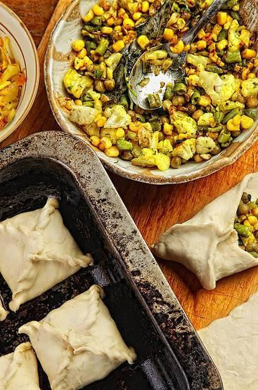 1. Этап. Слоеные пирожки с овощной начинкой: Тесто размораживаем и готовим овощную начинку. Для этого в сковородке разогреем масло. В нем обжарим все специи - сначала семена горчицы (будут трещать и разлетаться, поэтому накрыть крышкой), далее добавляем имбирь, карри и куркуму. Затем засыпаем все овощи. Обжариваем их, помешивая, до полной готовности. Затем тесто нарезаем на прямоугольники и начинаем лепить пирожки.