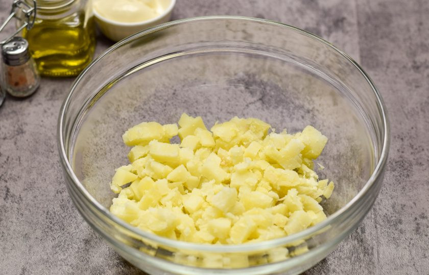 1. Этап. Салат Молдова: Картофель отварите в мундире и остудите, после почистите. Нарежьте картофель небольшими кубиками и переложите в салатник.