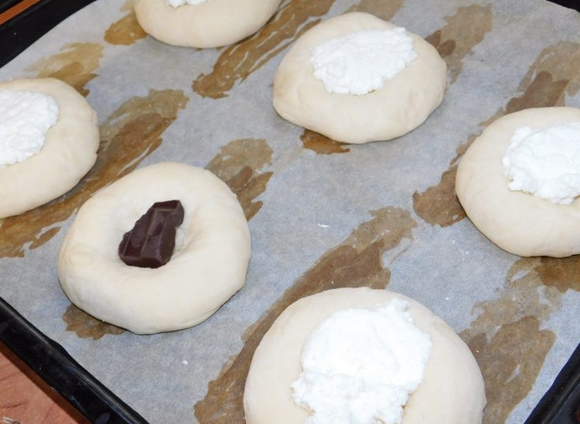 1. Этап. Сдобные ватрушки: Тесто разделите на маленькие булочки - примерно по 80 грамм. Дайте им немного подойти, затем сделайте с помощью стакана выемки для начинки. Положите по кусочку шоколада и сверху начинку. Бока смажьте желтком. Поставьте в духовку, разогретую до 200 градусов, минут на 15-20.