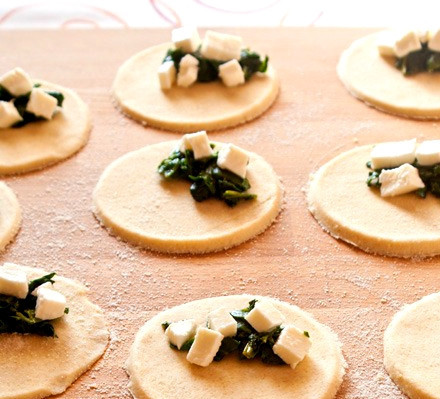 1. Этап. Вареники со шпинатом: Отрываем от теста комочки. Скатываем из них колбаски. От колбасок отрезаем кусочки теста. Затем раскатываем их как можно тоньше, но не слишком, просвечиваться они не должны. Сверху кладем начинку, тщательно защипываем края.