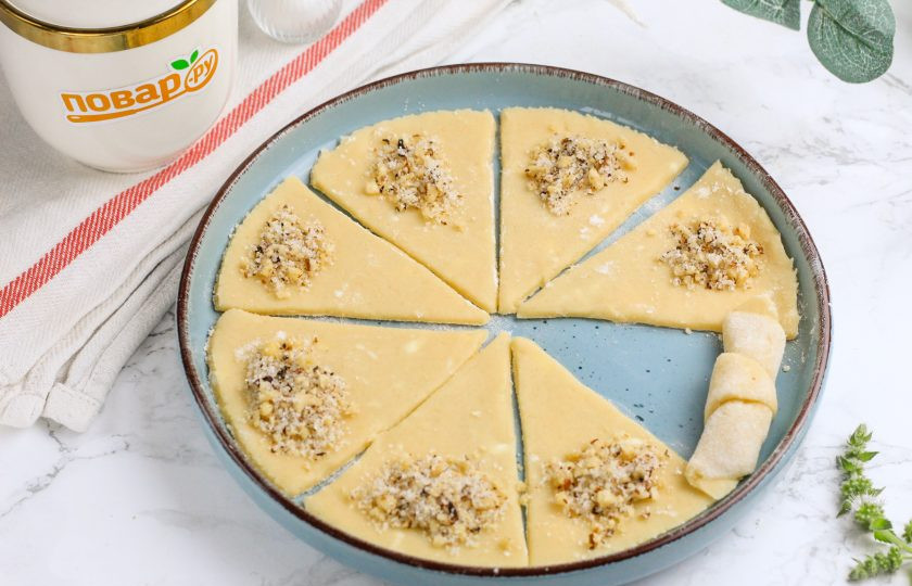 1. Этап. Рогалики песочные с орехами: На широкий край каждого треугольника всыпьте 1/2 ч.л. ореховой начинки. Затем, начиная именно с широкой части, скрутите треугольник рулетиком.