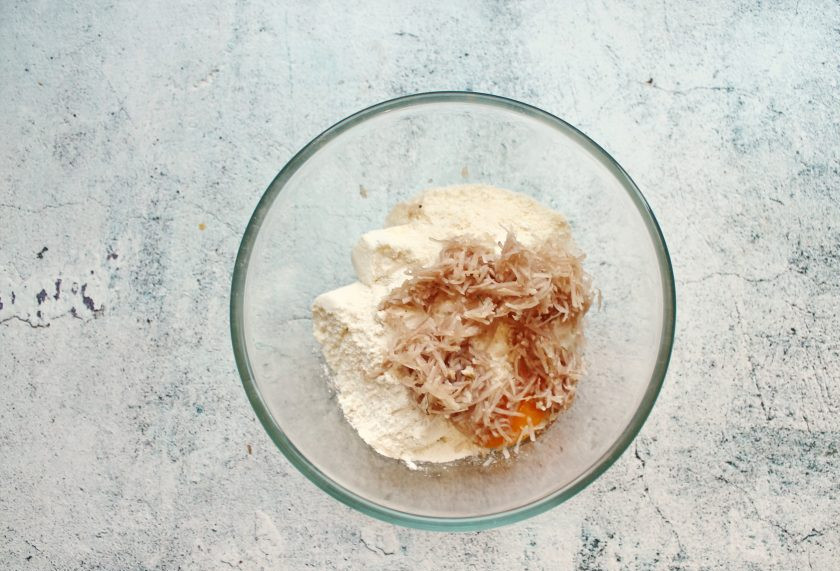 1. Этап. Сырники с топинамбуром: Оба вида муки смешайте с разрыхлителем, мукой и добавьте в миску с творогом. Топинамбур очистите от кожуры и натрите на мелкой терке.