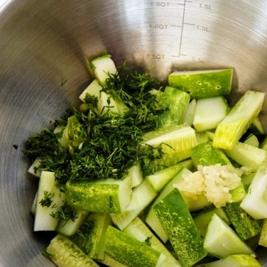 1. Этап. Салат из огурцов: Добавляем к огурцам нарубленную зелень и измельченный чеснок.