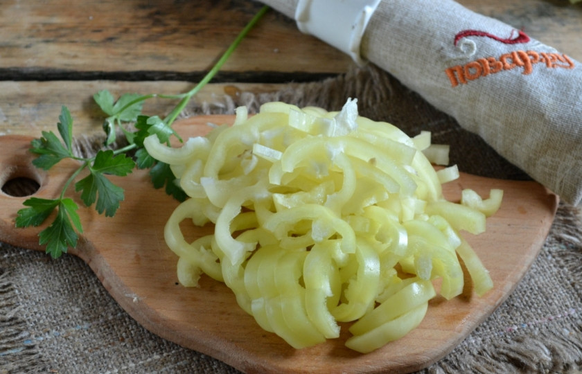 1. Этап. Лук в томатной заливке на зиму: Болгарский перец разрежьте пополам, удалите серединку с семенами и плодоножки. Нарежьте соломкой.