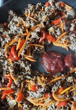 1. Этап. Соус Болоньезе по-азиатски: В середине сковородки отодвинуть фарш в сторону, добавить пасту кочудян и обжарить её пару минут.