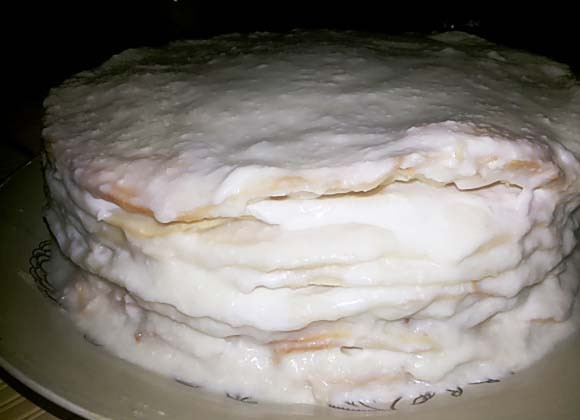 1. Этап. Торт Наполеон старый: Оставьте сложенные коржи с кремом на 60 минут. Потом сверху выложите пищевую плёнку и тарелку. Слегка прижмите выпечку и оставьте ещё на 30 минут. Далее уберите тарелку с бумагой. Сверху добавьте крем.