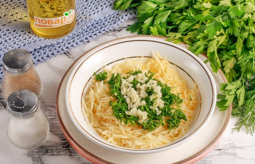 1. Этап. Мидии, запеченные с сыром в духовке: Пока мидии варятся, натрите твердый сыр любого сорта на терке с крупными ячейками в пиалу или креманку. Очистите чесночные зубчики и промойте их вместе с зеленью петрушки. Измельчите и добавьте к сыру вместе с щепоткой соли и молотым черным перцем. Аккуратно перемешайте.