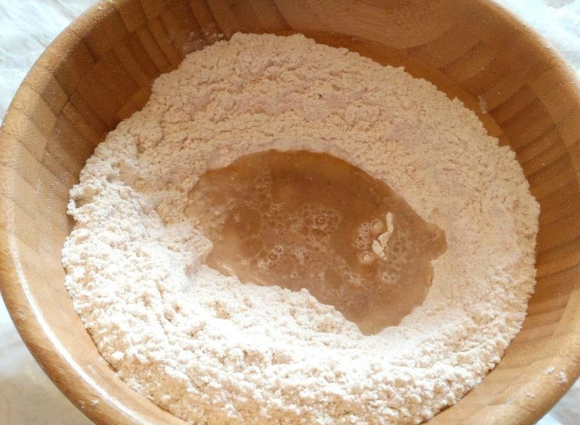 1. Этап. Лепёшки «Фатир» в духовке: Соедините сухие компоненты и сформируйте мучную горку с углублением в центре, влейте в него 2 ст. л. подсолнечного масла (оставшееся масло необходимо для смазывания теста в процессе формования лепёшек) и воду.