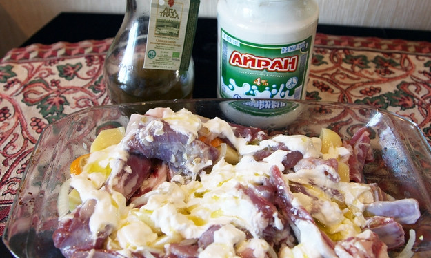 1. Этап. Бараньи ребрышки в духовке с картошкой: На дно жаропрочной формы вливаем оливковое масло. Выкладываем лук, измельченный чеснок. Выжимаем лимон и кладем дольки туда же, добавляем порезанный ломтиками картофель и ребрышки. Присыпаем специями, добавляем айран. Перемешиваем.