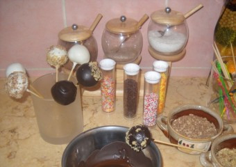 1. Этап. Пирожные на палочке: Когда все шарики будут с палочками, начинаем купать их в шоколаде :) Начинаем с того шарика, в который первым воткнули палочку. Окунаем шарик в шоколад, слегка встряхиваем и затем обваливаем в разноцветной посыпке, кокосовх стружках, измельченных вафельках - в чем захочется:) Украшенное пирожное надо подсушить. Можно втыкать палочки в кусок пенопласта, можно вставить в стаканчики. Главное, чтобы шарики-пирожные не соприкасались между собой.