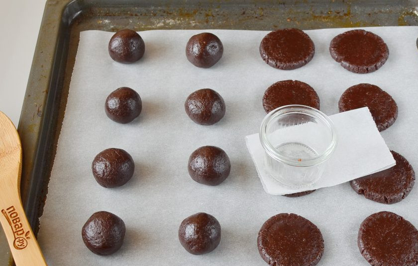 1. Этап. Мягкое шоколадное печенье: Соберите тесто в ком, разделите на 16 частей (я режу ножом пополам каждый раз, пока не станет 16 равных частей, это удобно). Скатайте в шарики комочки теста, выложите на пергамент. Возьмите кусочек пергамента и стаканчик с плоским дном, на каждый шарик теста выложите пергамент, придавите стаканчиком, чтобы придать форму печенью.