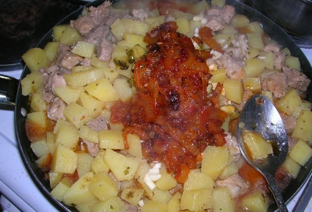 1. Этап. Азу с картошкой: 6. Чеснок очистить, выдавить через пресс или нарезать небольшими кусочками. Соединить мясо с картофелем с томатным соусом и огурцами. Залить водой или заранее приготовленным бульоном. Добавить чеснок, лавровый лист, посолить и поперчить по вкусу. Оставить тушиться под закрытой крышкой до готовности. Азу с картошкой в домашних условиях перед подачей можно украсить свежей зеленью.