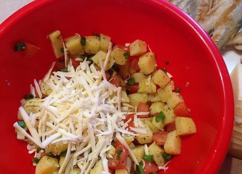 1. Этап. Запеканка с корюшкой: 3. Смешаем в миске картофель, помидоры, зеленый лук. Добавим немного сыра, натертого на терке, сушеный базилик, посолим и поперчим. перемешаем.