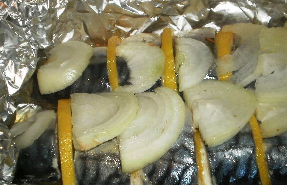 1. Этап. Копченая скумбрия в мультиварке: Чай и сахар смешайте и распределите на большом листе фольги, сверху положите меньший лист. На нем разместите кусочки рыбы, переложив их дольками лимонов и лука. В брюшки рыбы вложите веточки укропа.