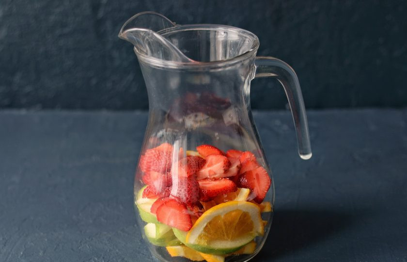 1. Этап. Безалкогольная Сангрия: Апельсин, яблоко и клубнику нарежьте на ломтики среднего размера. Переложите в кувшин.