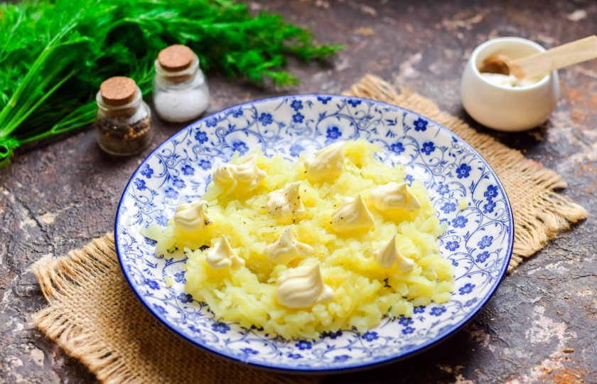 1. Этап. Салат Лебединый пух с пекинской капустой: Картофель натрите на средней терке, выложите первым слоем на тарелку, смажьте майонезом.