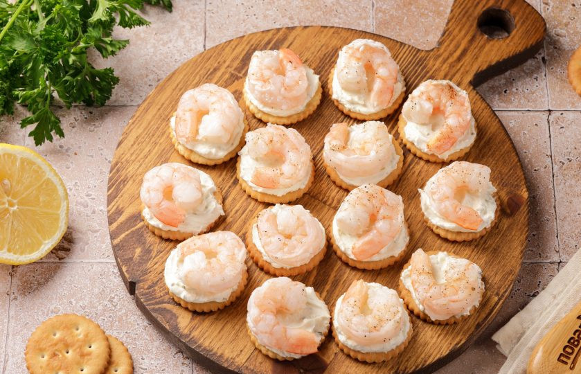 1. Этап. Канапе с креветкой на крекере: На крекеры с сыром выложите креветки.