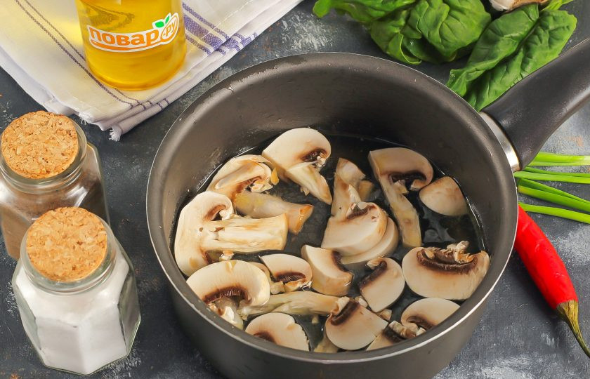 1. Этап. Рамен с сыром: Влейте куриный бульон в сотейник или ковш, всыпьте соль и молотый черный перец. Промойте шампиньоны и нарежьте их крупными слайсами. Добавьте в бульон и проварите все примерно 5-8 минут.