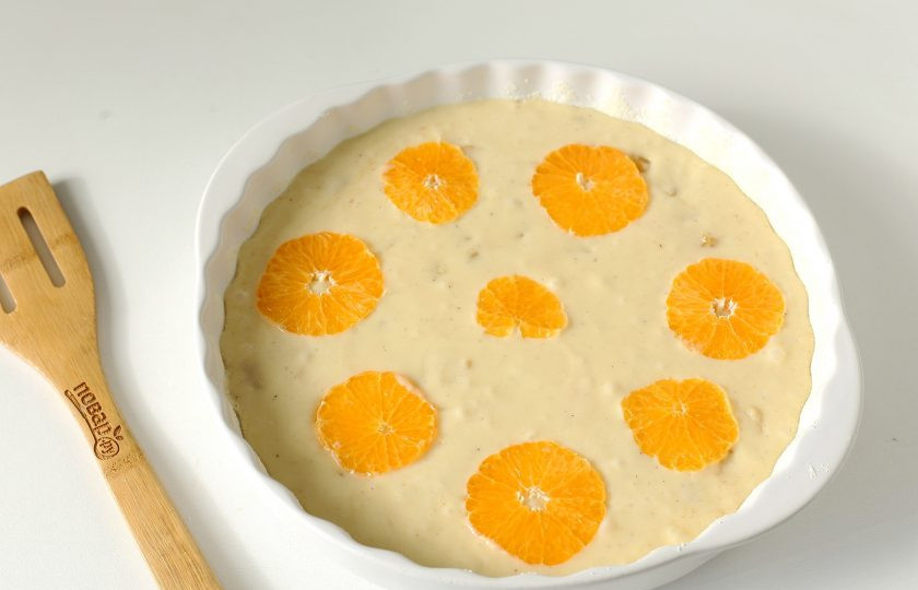 1. Этап. Пирог с мандаринами на кефире: Сделайте несколько круговых движений лопаткой и переложите тесто в смазанную маслом форму для выпечки. Дно и бока можно обсыпать мукой или манкой. Оставшийся мандарин нарежьте кружочками и украсьте пирог сверху. Выпекайте в духовке при температуре 200 градусов около 40 минут.