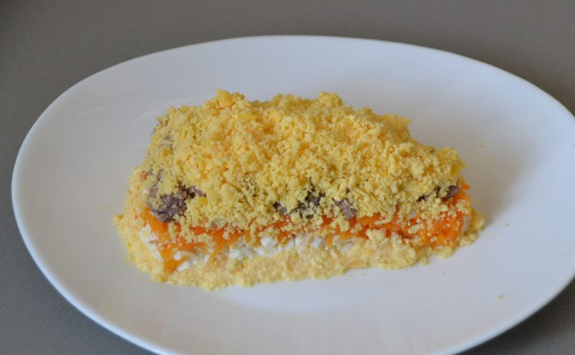 1. Этап. Салат Сырный ломтик на год Крысы: Верх и бока салата посыпьте отварными куриными желтками, натертыми на терке.