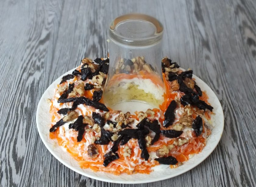 1. Этап. Салат Гранатовый браслет с черносливом и грецким орехом: Натрите на крупной терке морковь, разложите. Чернослив нарежьте соломкой, орехи крупно нарежьте. Выложите на морковный слой.