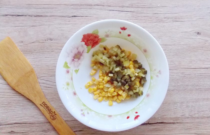 1. Этап. Салат Желтый одуванчик с кукурузой: Мелко нарежьте маринованные огурцы и добавьте к кукурузе.