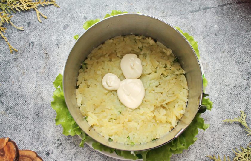 1. Этап. Салат с красной рыбой и креветками слоями: Картофель почистите и натрите на крупной терке. На салат установите сервировочное кольцо диаметром 15 сантиметров и выложите половину картофеля плотным слоем. Смажьте картофель майонезом.