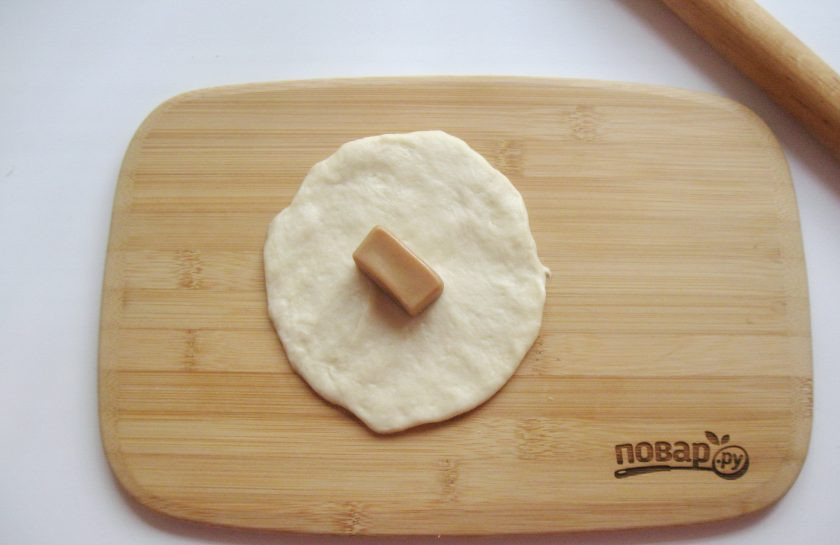 1. Этап. Пирожки с конфетами: Каждый шарик раскатайте в лепешку, на середину которой выложите конфету. У меня 