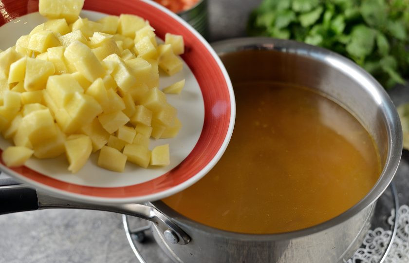 1. Этап. Фасолевый суп с кинзой: Влейте теплую воду из чайника, добавьте в сотейник нарезанный кубиком картофель, варите суп минут 10.