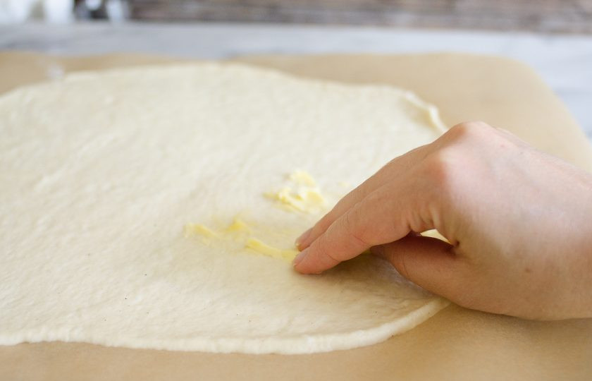 1. Этап. Начинка для пиццы с фаршем: 4. Тем временем тесто уже подошло. Выложите на стол пергамент и раскатайте на нем тесто в тонкий пласт, смажьте его маленьким кусочком сливочного масла.