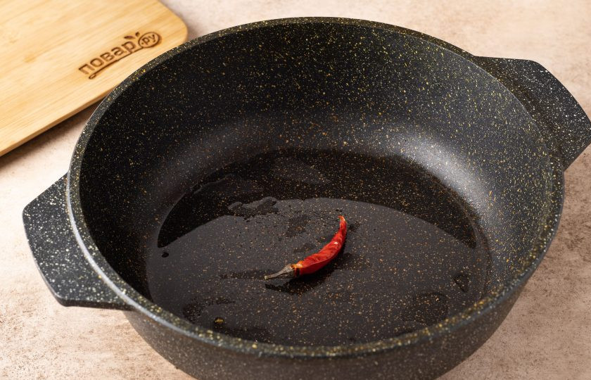 1. Этап. Тайское блюдо из рисовой лапши: Разогрейте сковороду с растительным маслом и обжарьте в ней стручок перца чили до раскрытия аромата. Затем уберите чили.