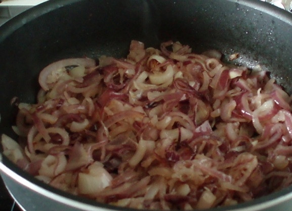 1. Этап. Луковый джем: Лук сначала очистите от шелухи, затем нарежьте его тонкими полукольцами. Обжарьте овощ на раскалённом масле с солью в течение 7-10 минут до коричневого цвета.