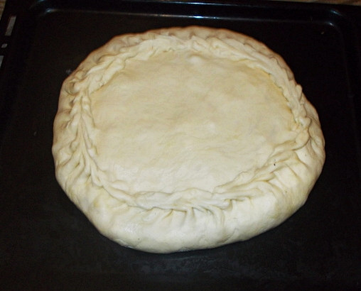 1. Этап. Курник с картошкой: Следующий шаг - выложить начинку на тесто и накрыть вторым куском теста, который поменьше. Закрепить края. Сверху курник можно смазать яичным желтком. Поставить в духовку на пол часа. Духовка должна быть разогрета до 220 градусов.