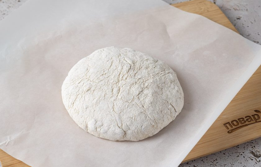 1. Этап. Ржано-пшеничный хлеб с семечками: Переверните тесто швом вниз и выложите на присыпанный мукой пергамент для выпечки. Накройте чистым кухонным полотенцем и оставьте на 1 час для расстойки. Параллельно включите духовку на максимум (у меня это 250 градусов) и поставьте в нее жаростойкую посуду для выпечки вместе с крышкой на 30 минут.